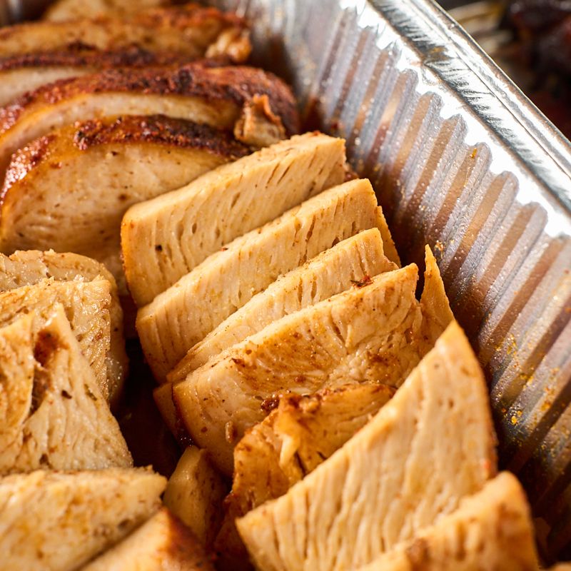 Sliced smoked chicken in a catering pan
