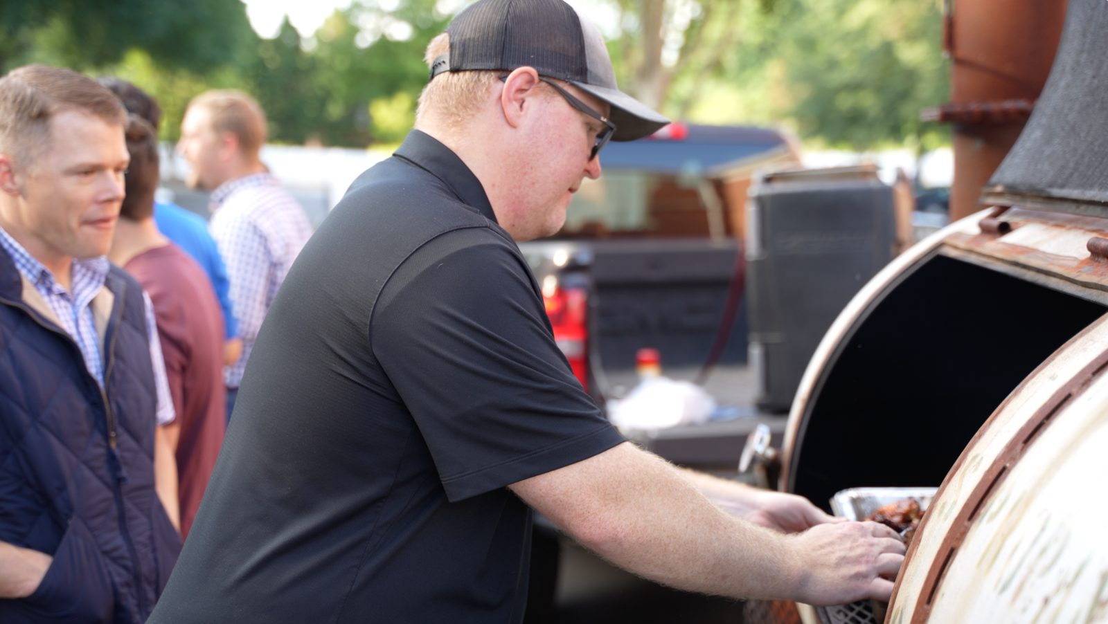 Patrick loading the smoker on-site at an event while guests look on