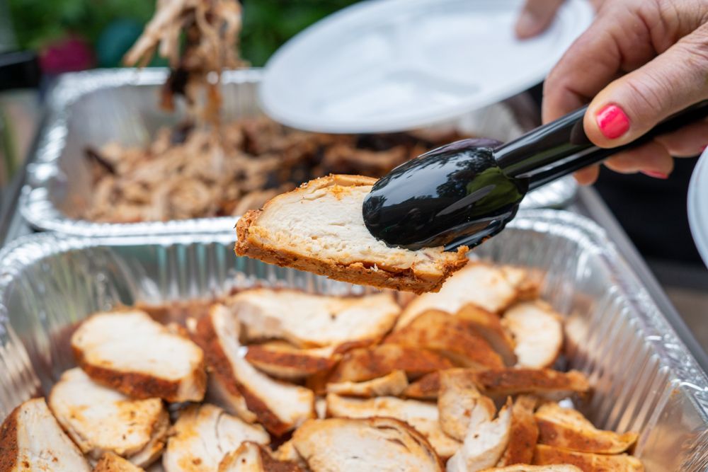 Tongs lifting a slice of smoked chicken