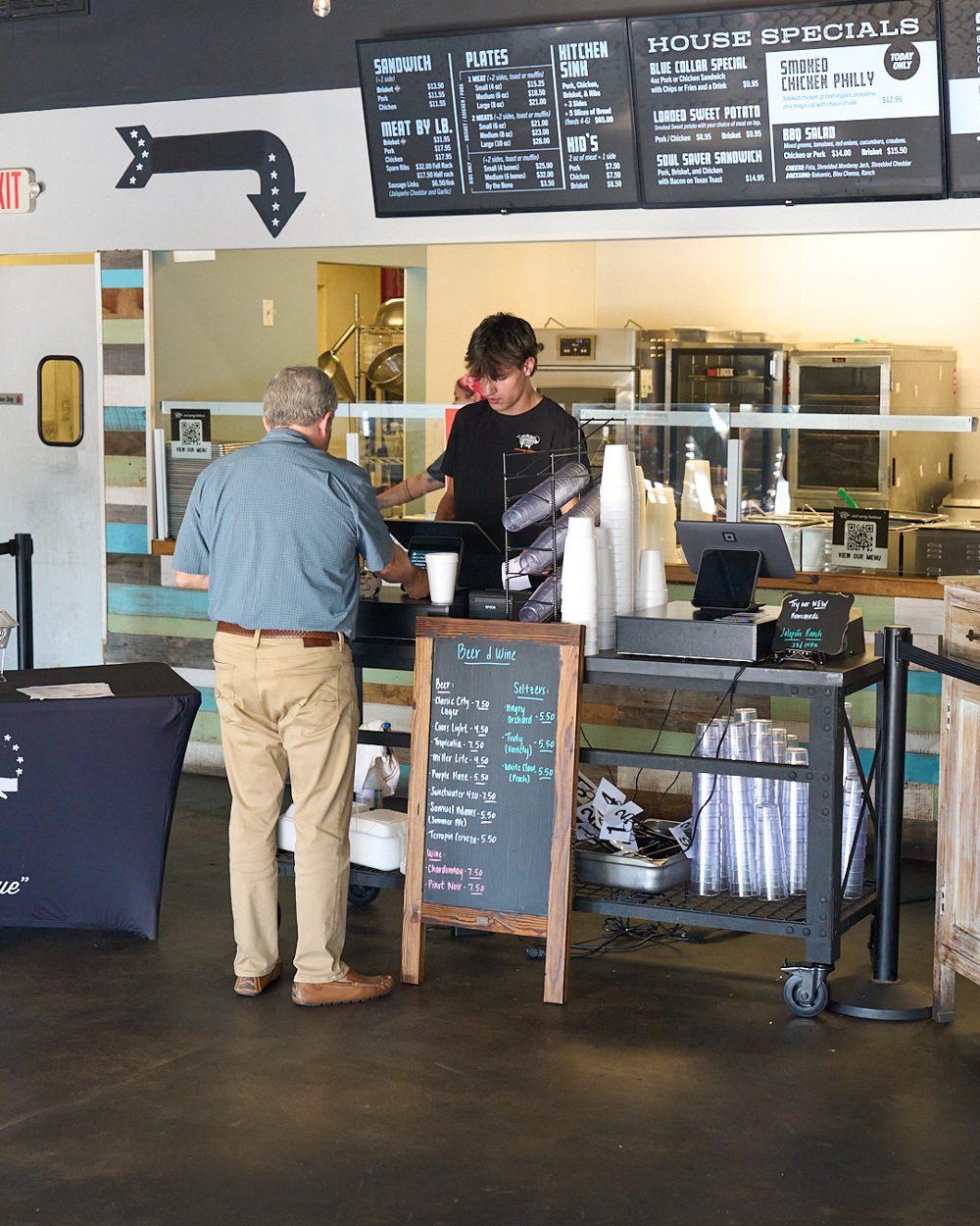 A guest ordering at the counter under the menu boards